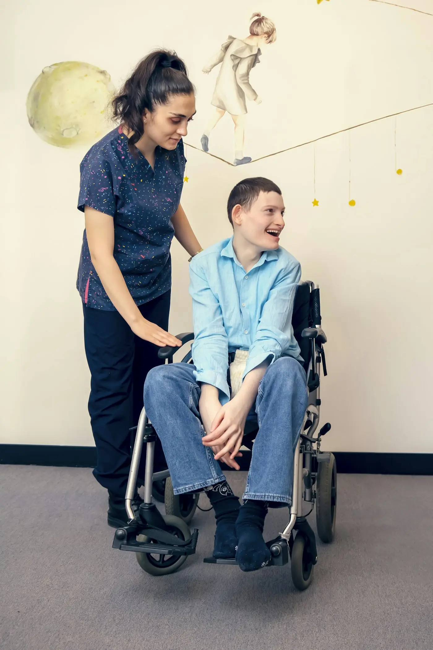 Support worker standing beside a smiling young man in a wheelchair