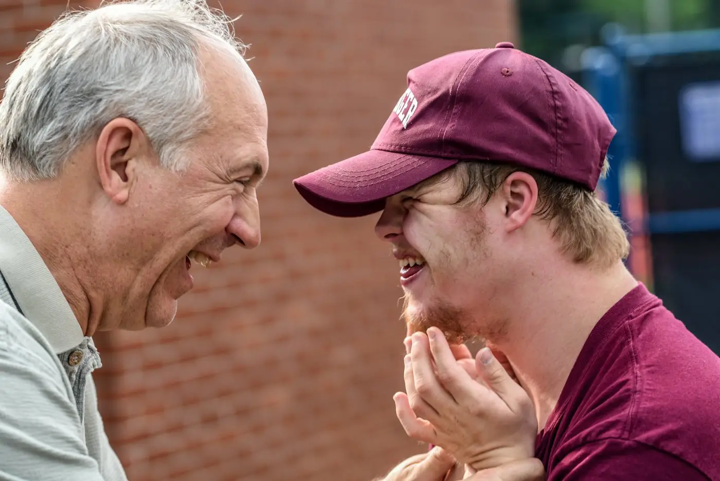 Older man and a young man in a cap laughing together