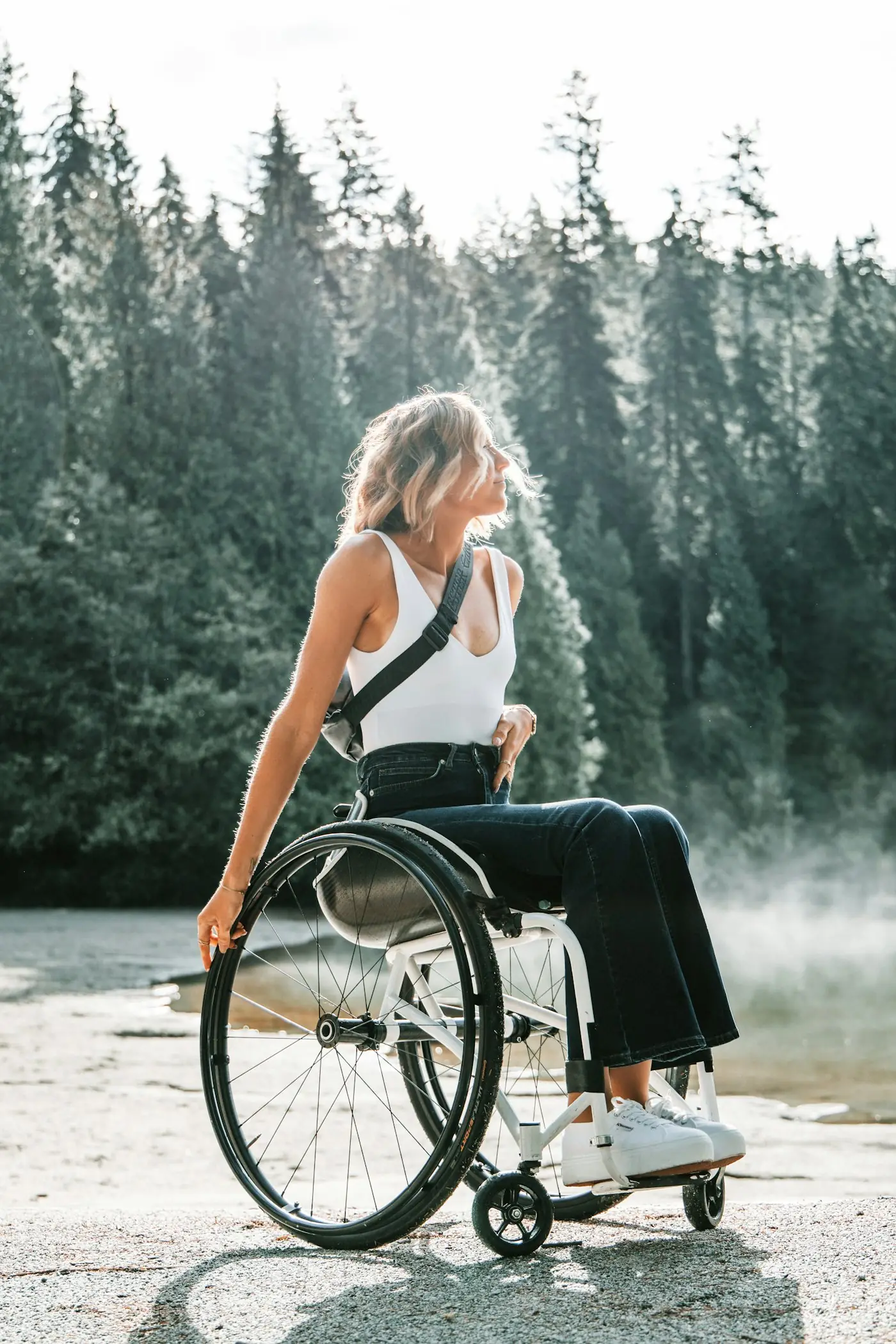 Woman using a wheelchair beside a misty lake surrounded by forest