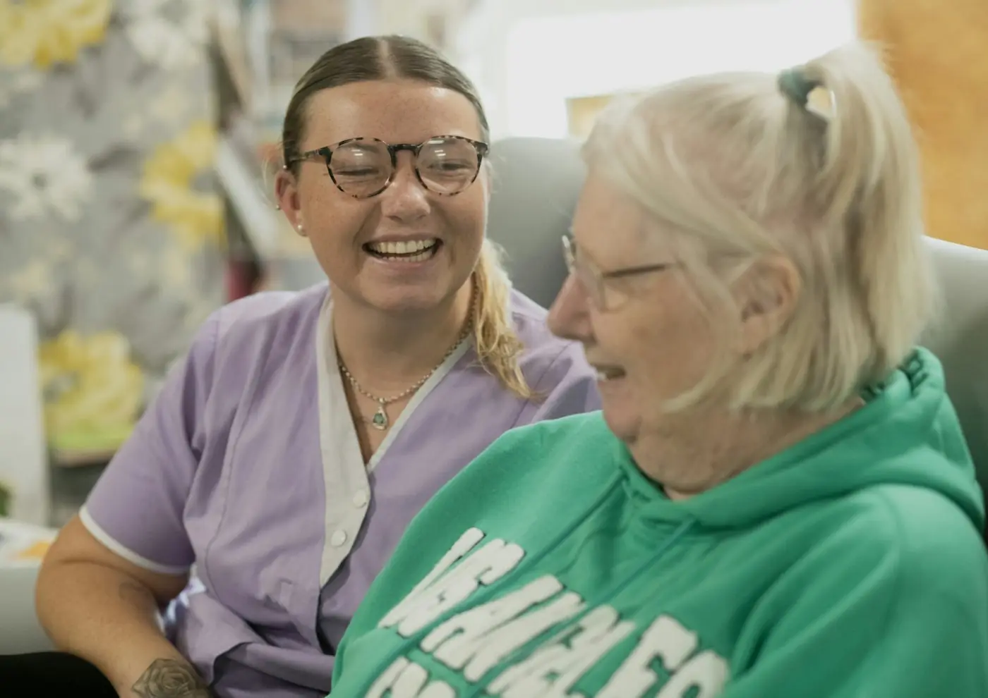 Support worker and an older woman laughing together