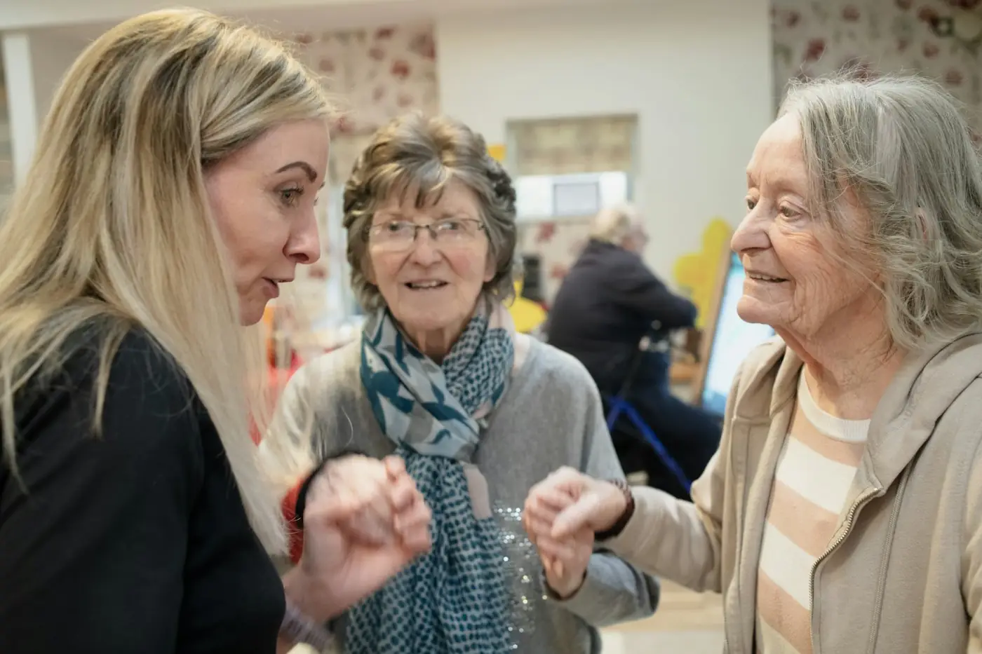 Three women talking warmly together indoors while going through paperwork